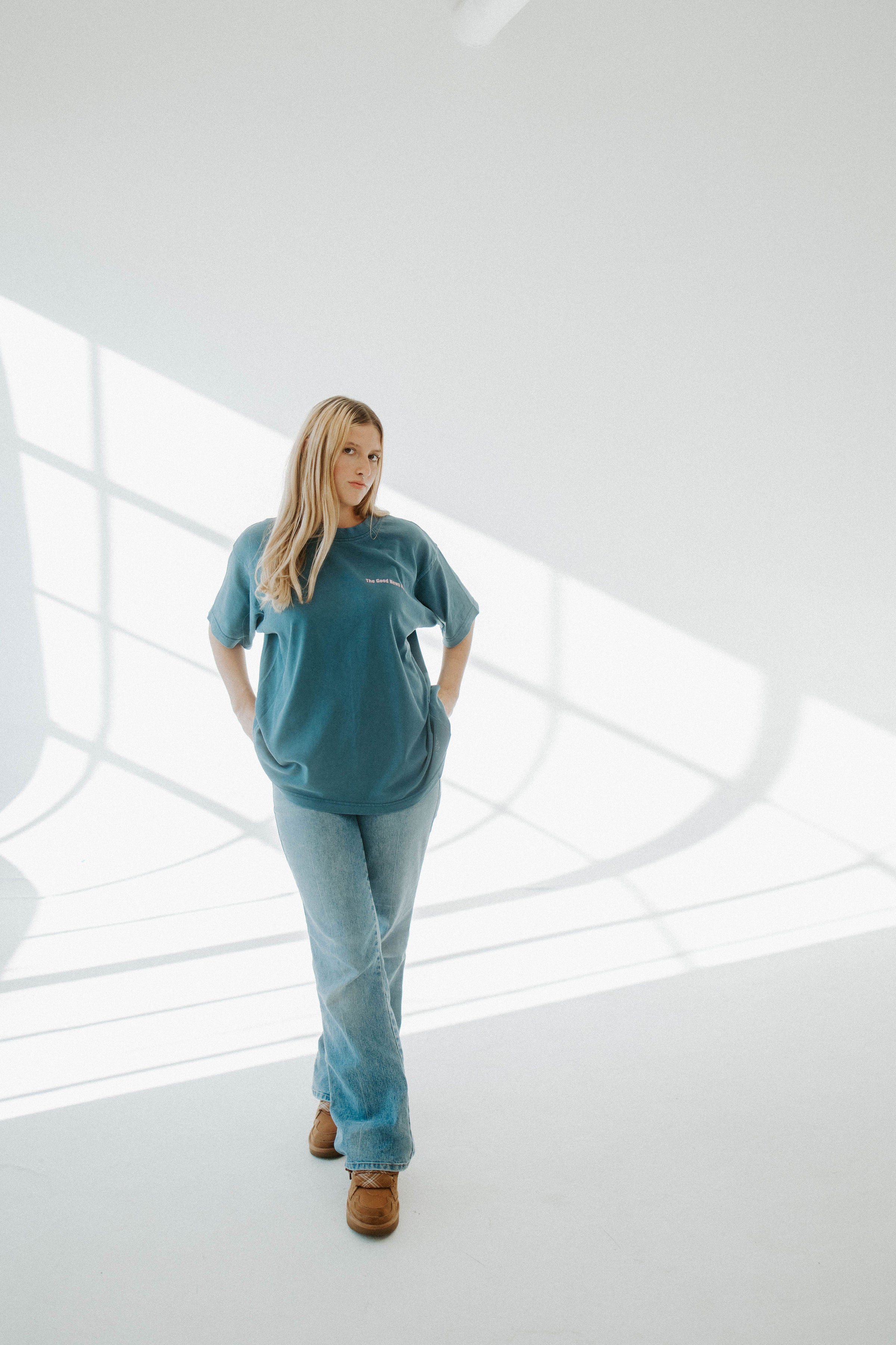 Woman wearing a teal outfit standing in a modern indoor setting with white walls and floor.