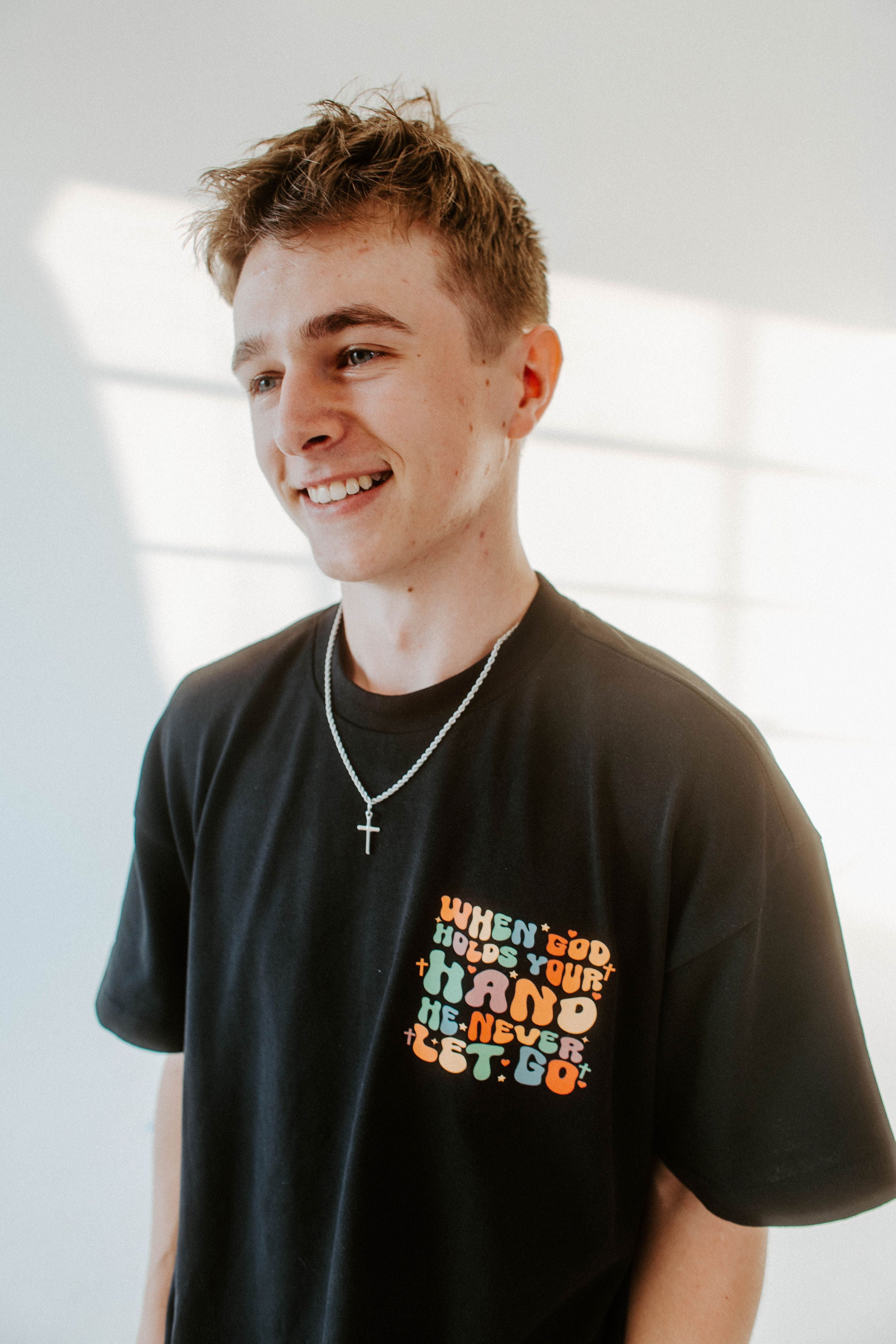 WHEN GOD HOLDS YOUR HAND TEE IN BLACK