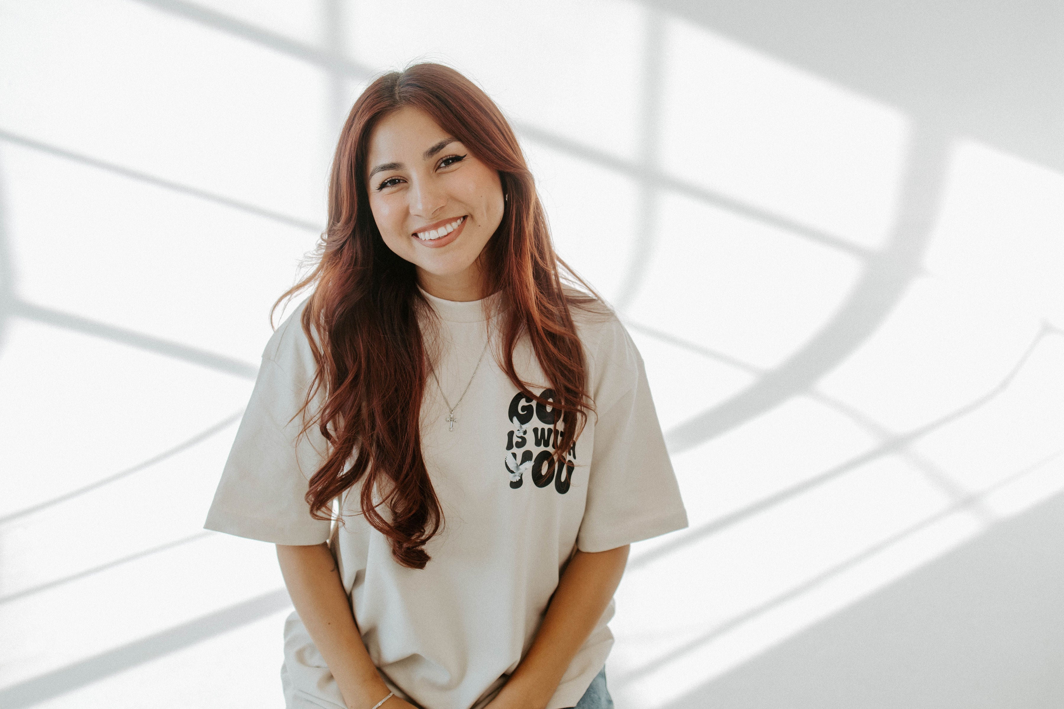 Woman wearing a white t-shirt with text, standing against a light background