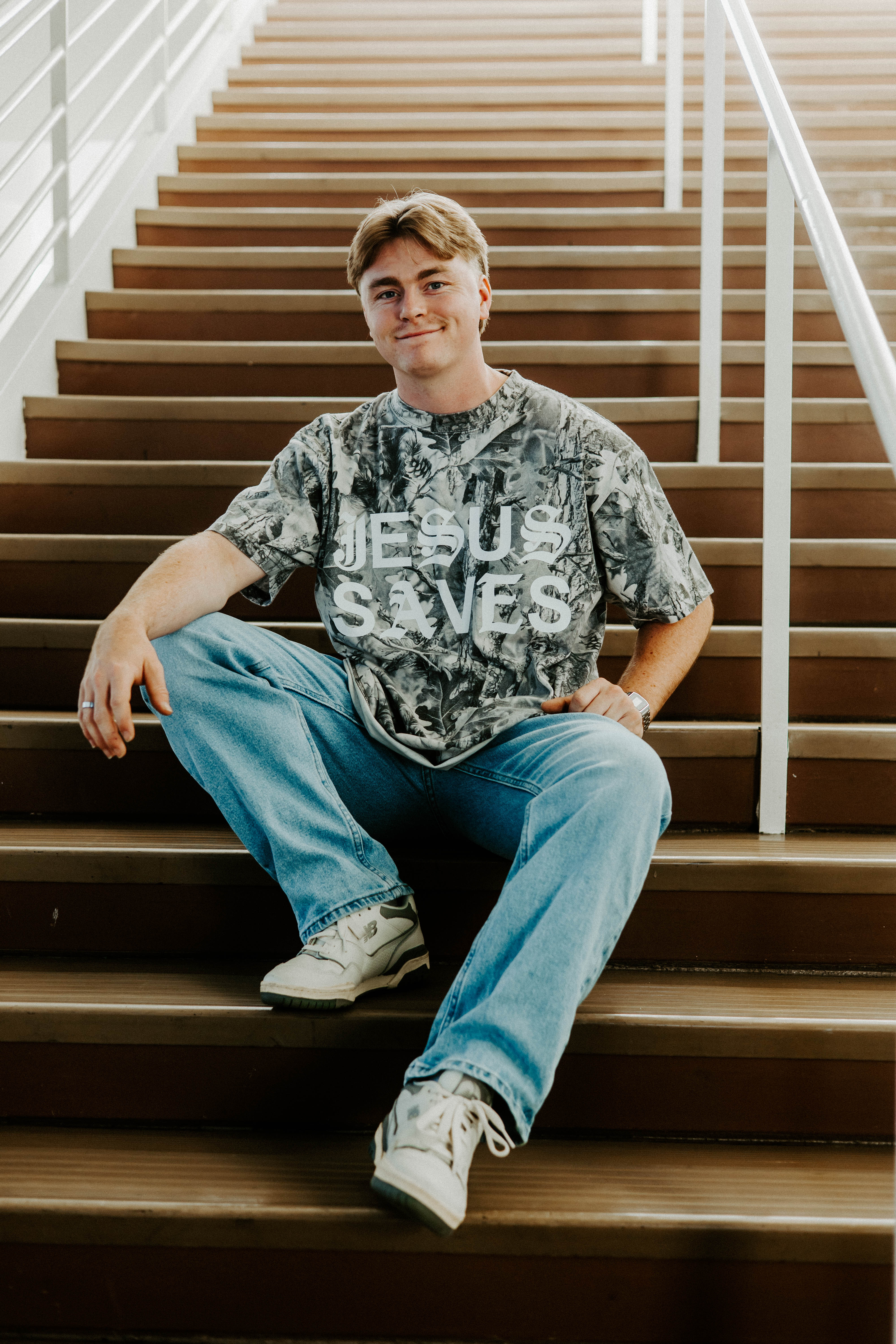 Person sitting on a staircase wearing a 'Jesus Saves' t-shirt