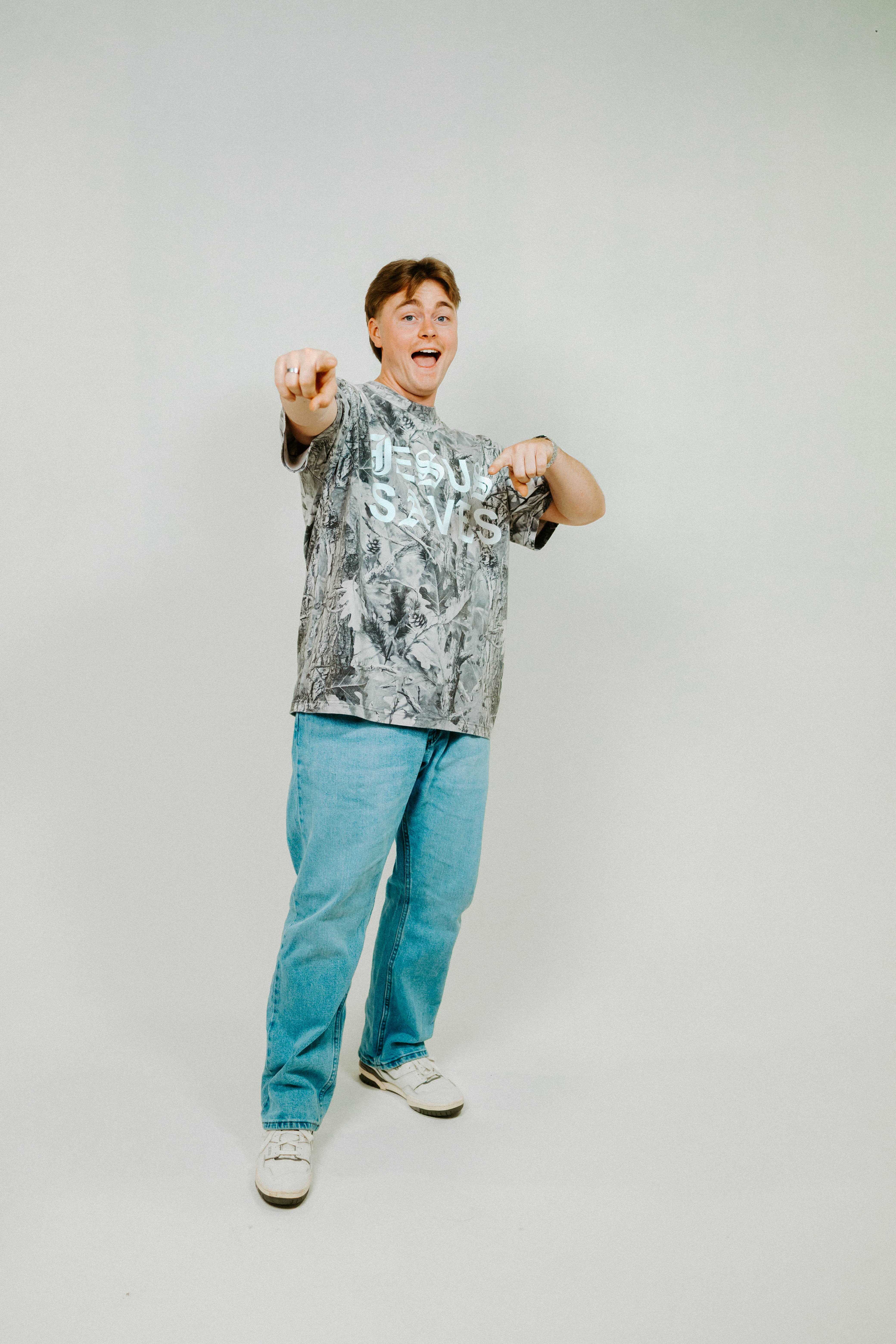 Person wearing a tie-dye shirt and blue jeans on a plain background