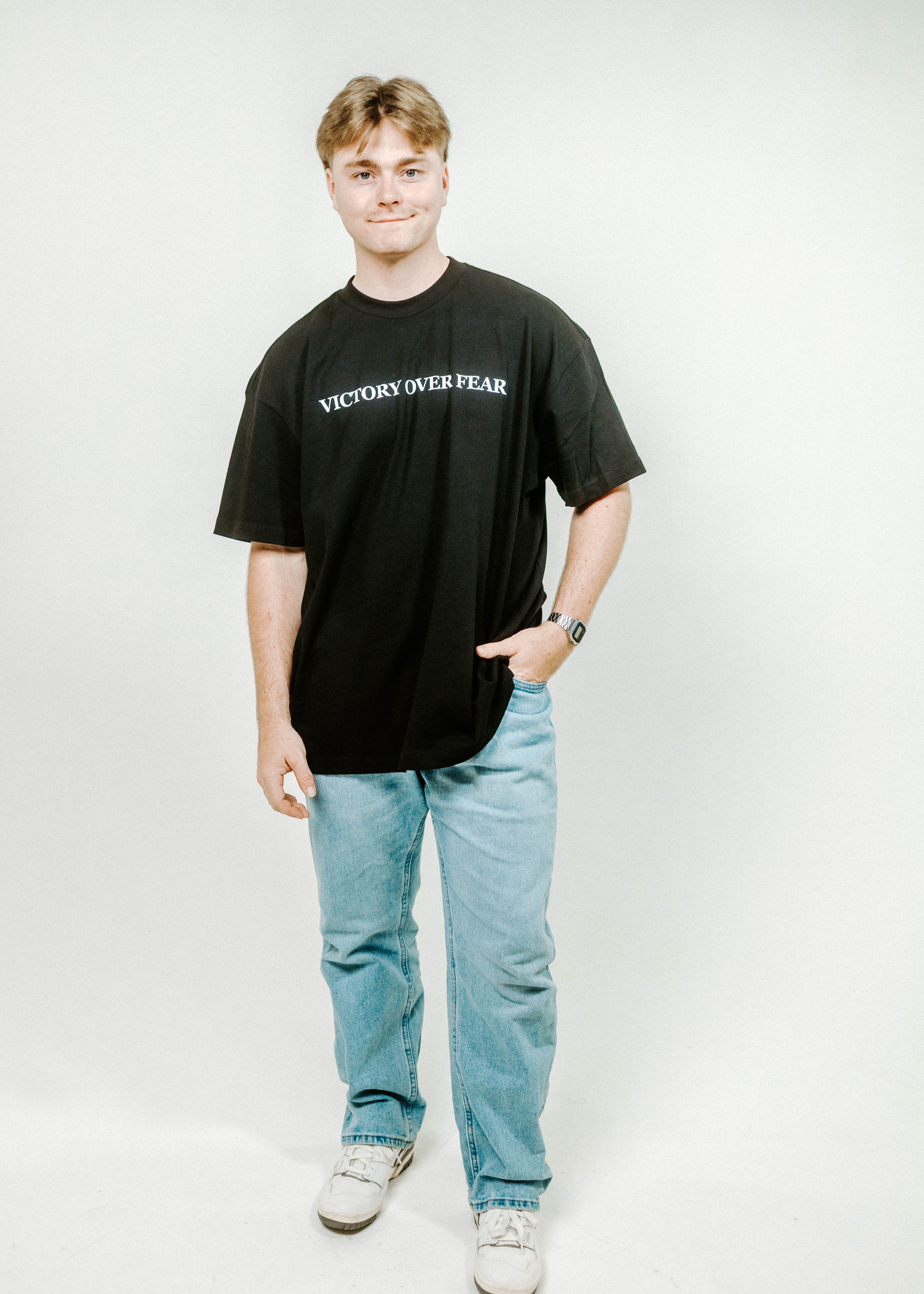 Person wearing a black t-shirt with 'VICTORY OVER FEAR' text on a white background