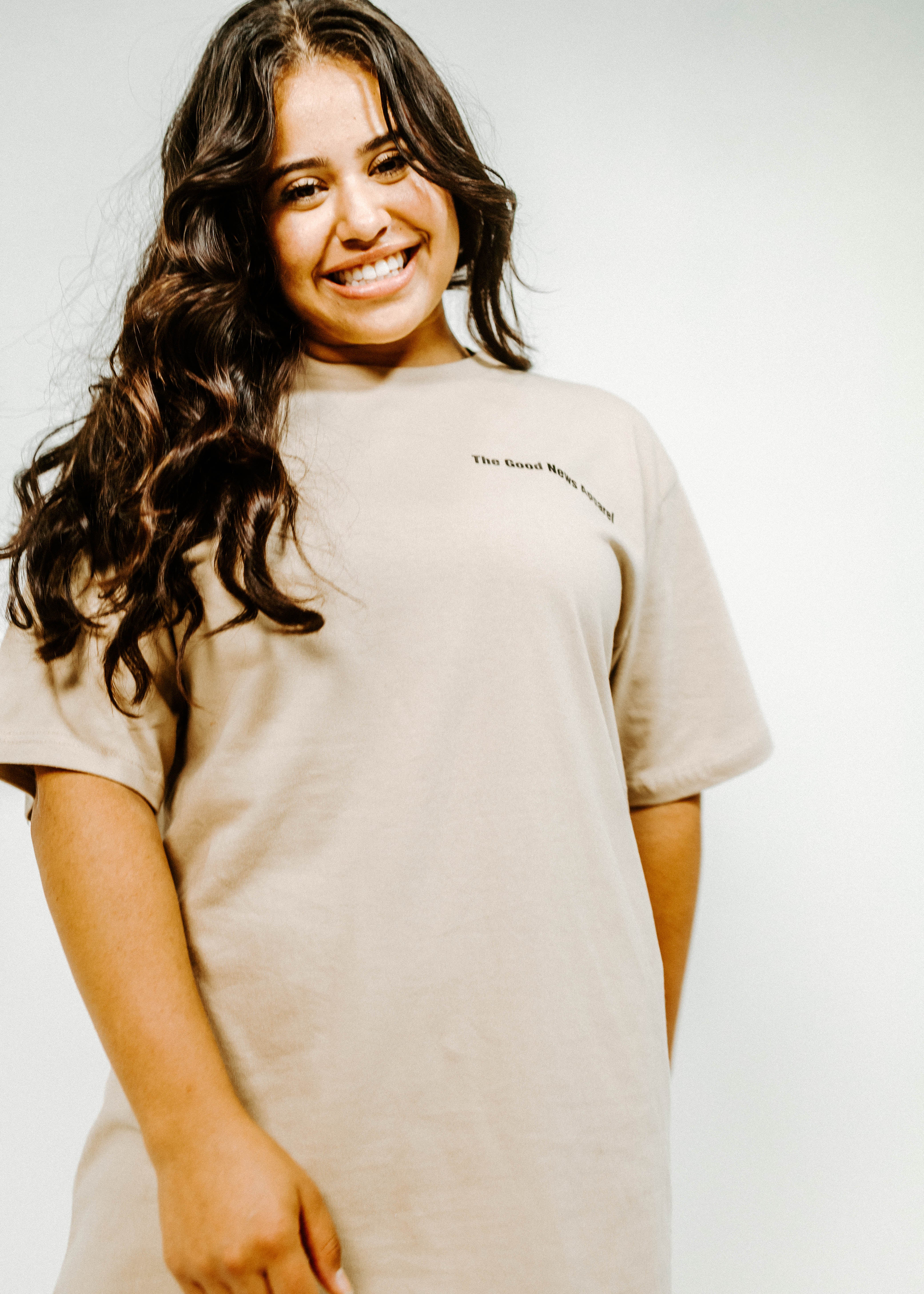Woman wearing a beige t-shirt with text on a plain background