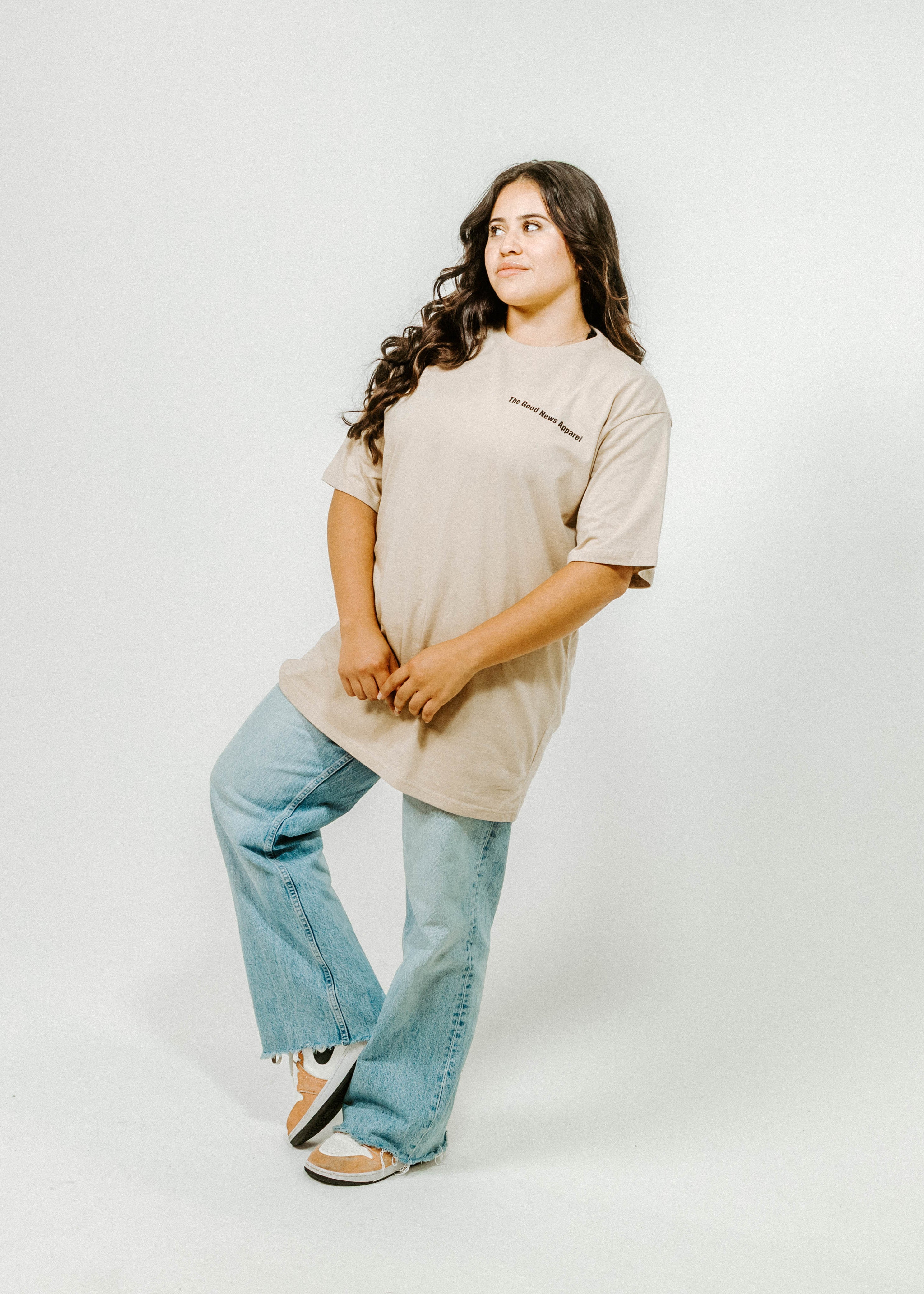 Woman wearing a beige shirt and blue jeans on a white background