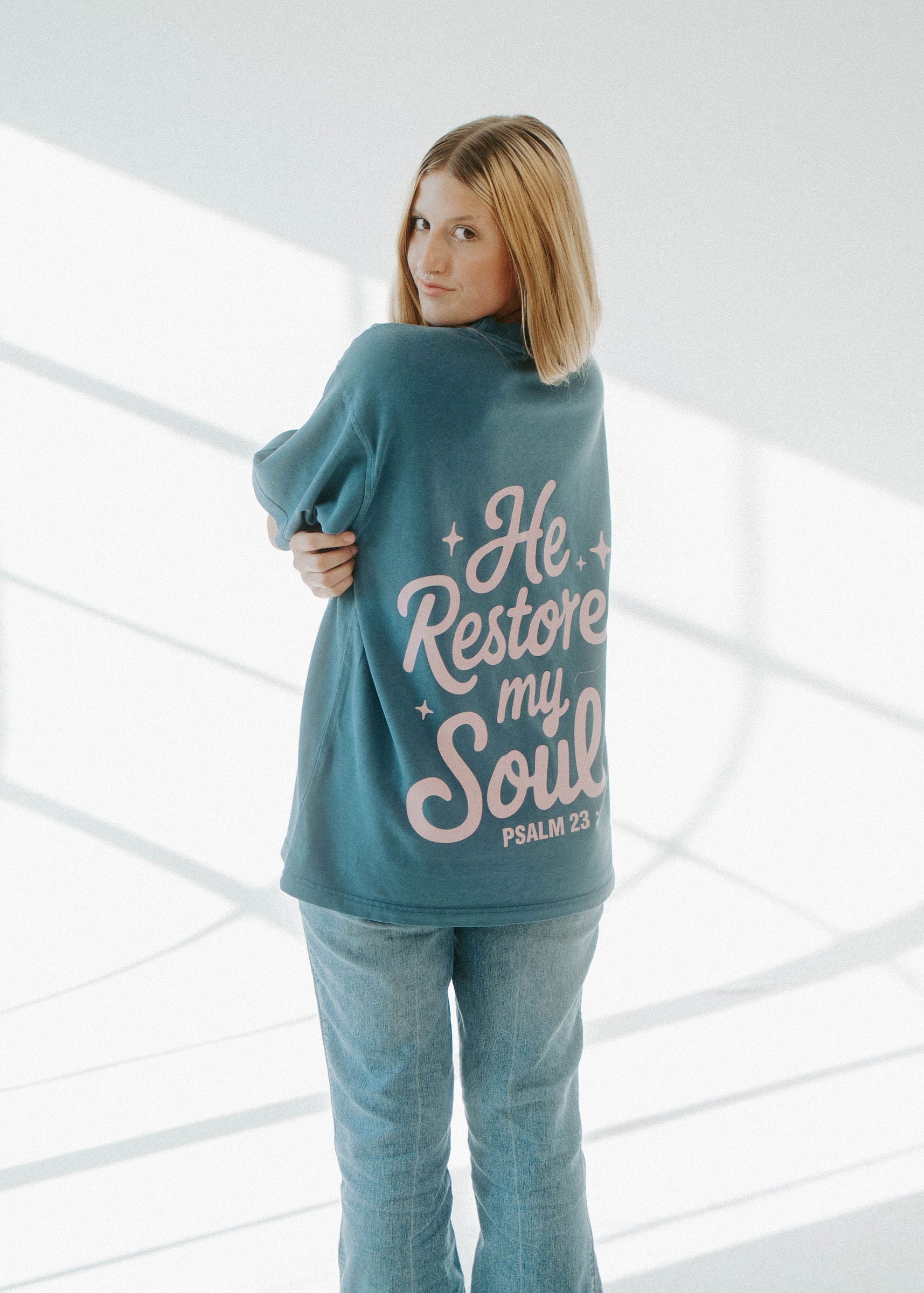 Woman wearing a teal sweatshirt with text in a modern, well-lit interior setting