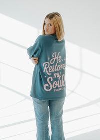 Woman wearing a teal sweatshirt with text in a modern, well-lit interior setting
