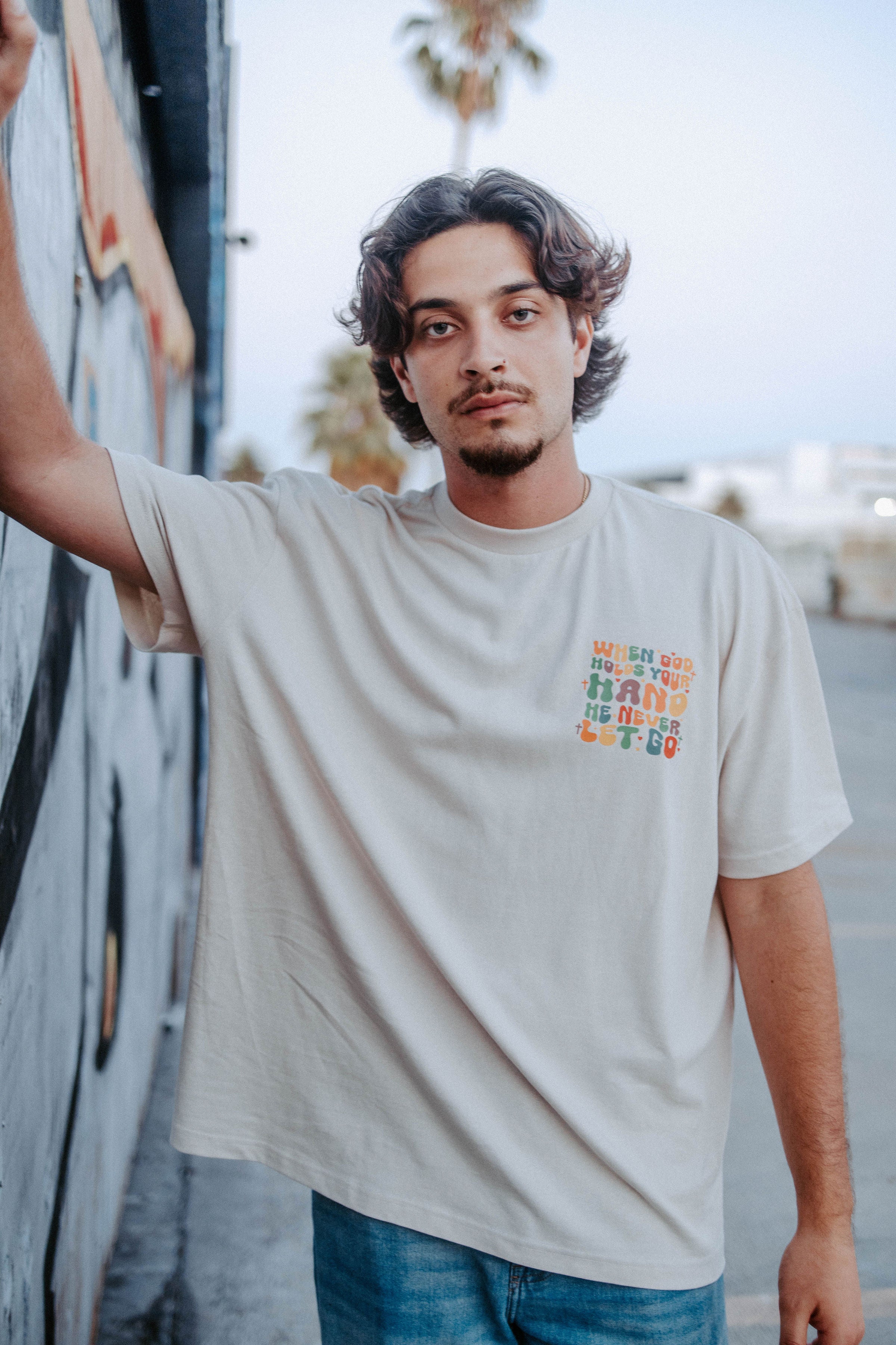 WHEN GOD HOLDS YOUR HAND TEE IN BEIGE