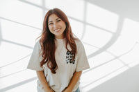 Woman wearing a white t-shirt with text, standing against a light background