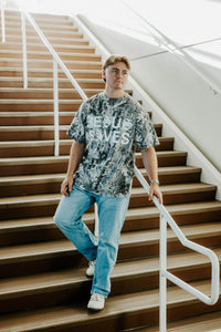Person wearing a t-shirt with text standing on a staircase indoors