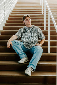 Person sitting on a staircase wearing a t-shirt with 'Jesus Saves' text.