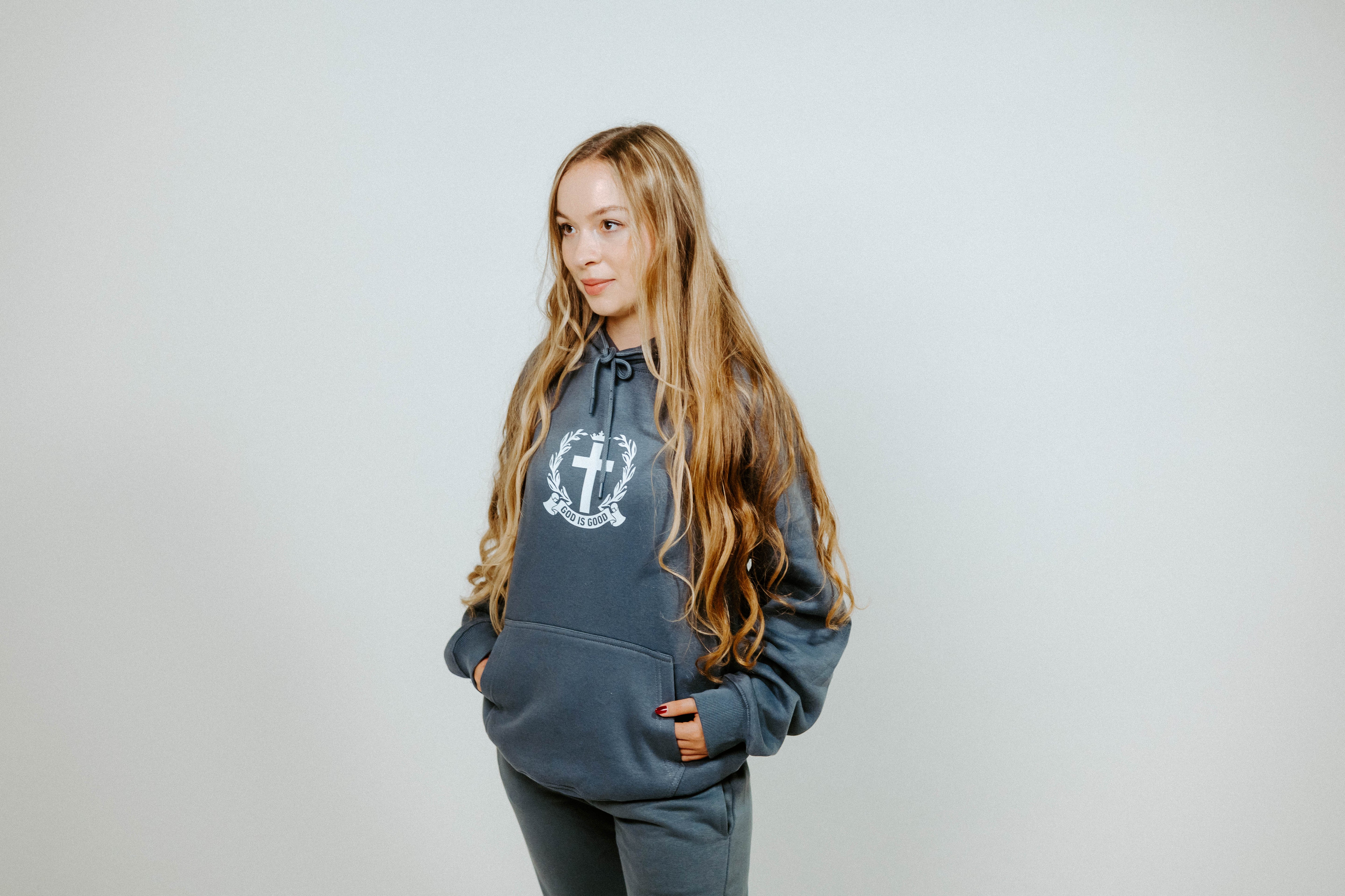 Woman wearing a gray hoodie with a logo on a plain background