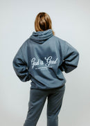 Person wearing a gray hoodie with 'God is Good' text on the back against a white background