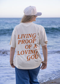 Woman wearing the Living Proof of a Loving God oversized Christian graphic tee in cream.