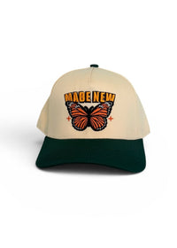 Beige and green cap with butterfly design and text on a white background