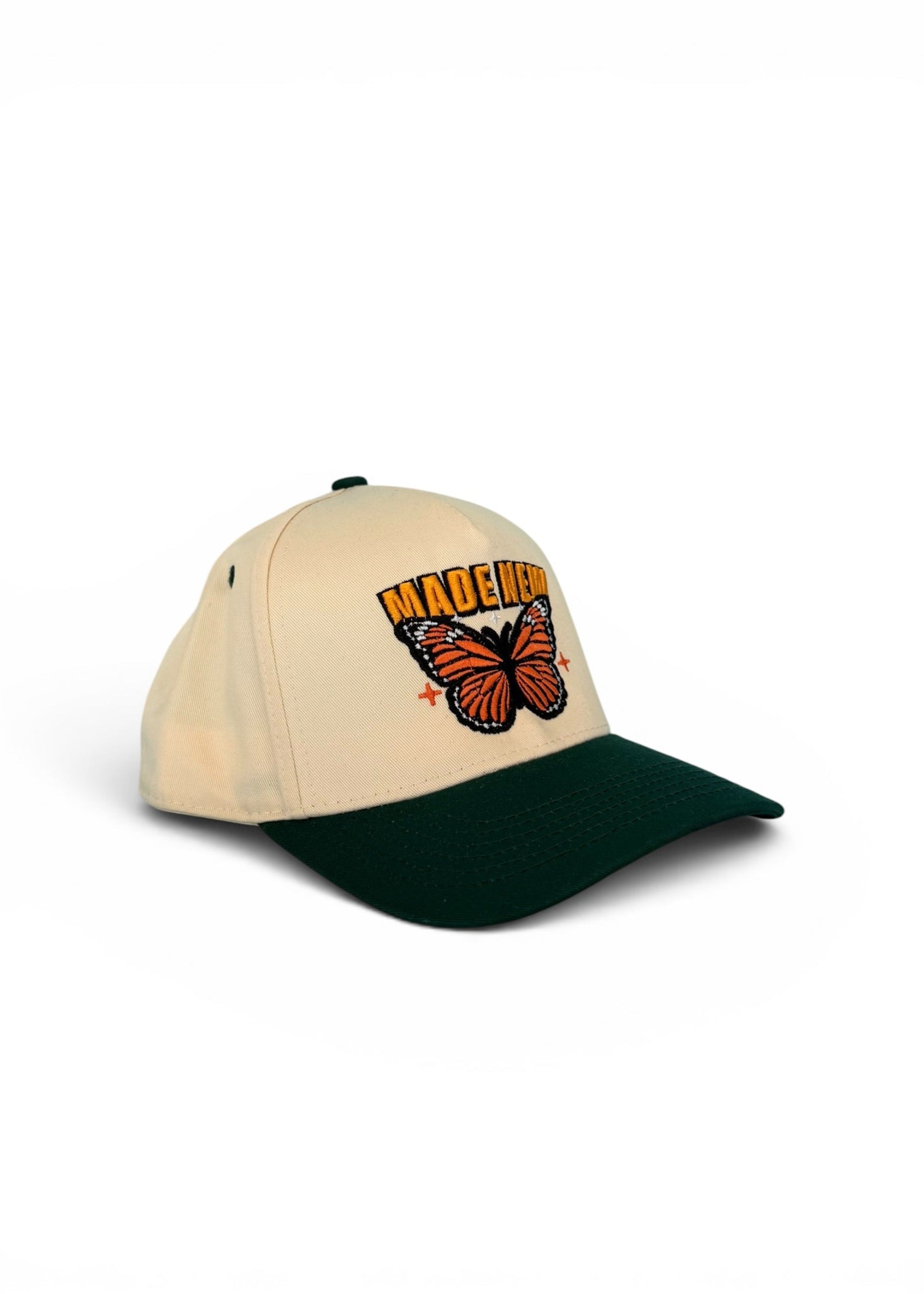Beige and green cap with butterfly design and 'Majestic' text on a white background