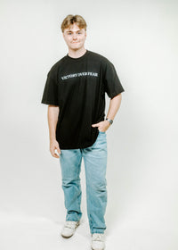 Person wearing a black t-shirt with 'VICTORY OVER FEAR' text on a white background