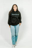 Person wearing a black hoodie with 'Victory Over Wear' text on a white background