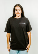 Person wearing a black t-shirt with text on a plain background