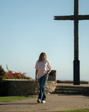 Person walking towards a large wooden cross against a clear blue sky.