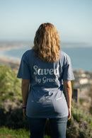 Person wearing a 'Saved by Grace' t-shirt overlooking a scenic view.