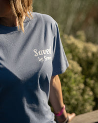 Person wearing a blue shirt with 'Saved by Grace' text, standing outdoors.