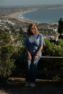 Person sitting on a bench with a scenic view of a beach and cityscape in the background