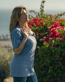 Woman standing outdoors with flowers and a scenic background