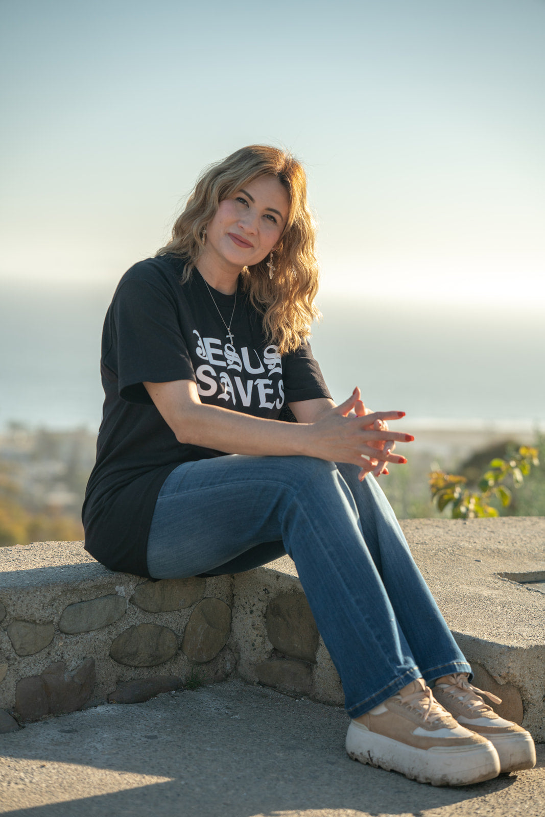 Woman sitting on a stone wall with a scenic background