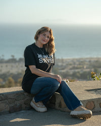 Woman sitting on a stone wall with a scenic view in the background