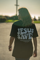 Person wearing a black t-shirt with 'JESUS SAVED' text outdoors.