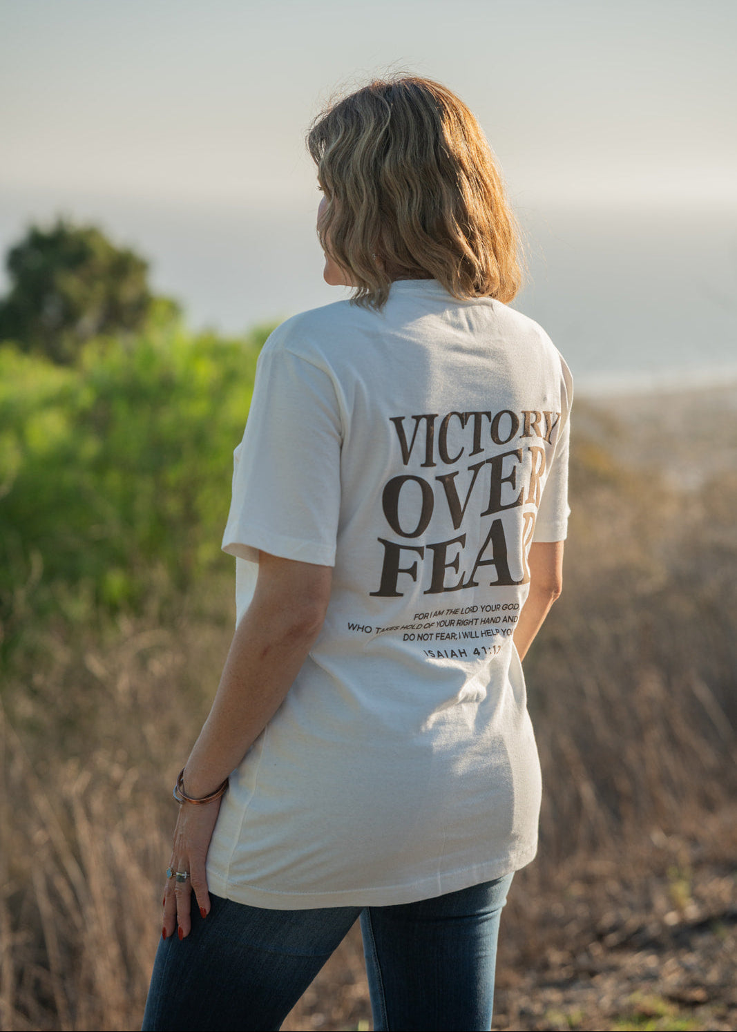 Person wearing a white t-shirt with 'Victory Over Fear' text outdoors.