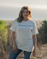 Woman wearing a white t-shirt with 'Victory Over Fear' text, standing outdoors.
