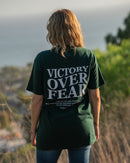 Person wearing a green t-shirt with 'Victory Over Fear' text, standing outdoors.
