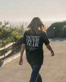 Person walking on a path with 'Victory Over Fear' t-shirt
