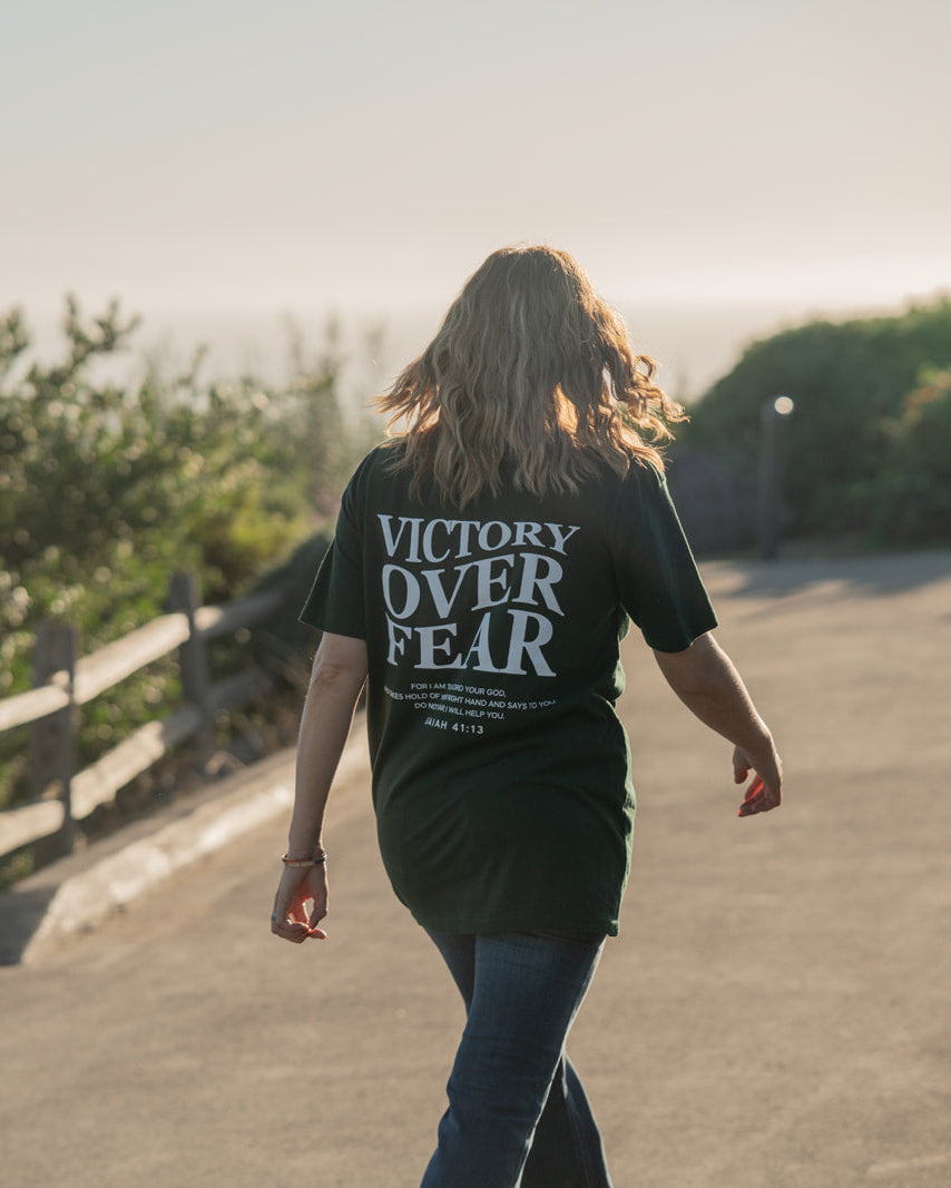 Person walking on a path with 'Victory Over Fear' t-shirt