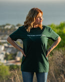 Woman wearing a green t-shirt with 'Victory Over Fear' text, standing outdoors with a scenic background.