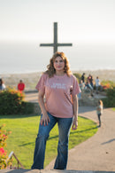 Woman wearing a 'Child of God' t-shirt standing in front of a cross