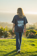 Person wearing a t-shirt with text walking on grass at sunset
