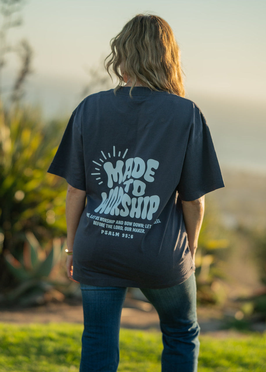 Person wearing a 'Made to Worship' t-shirt in a natural setting