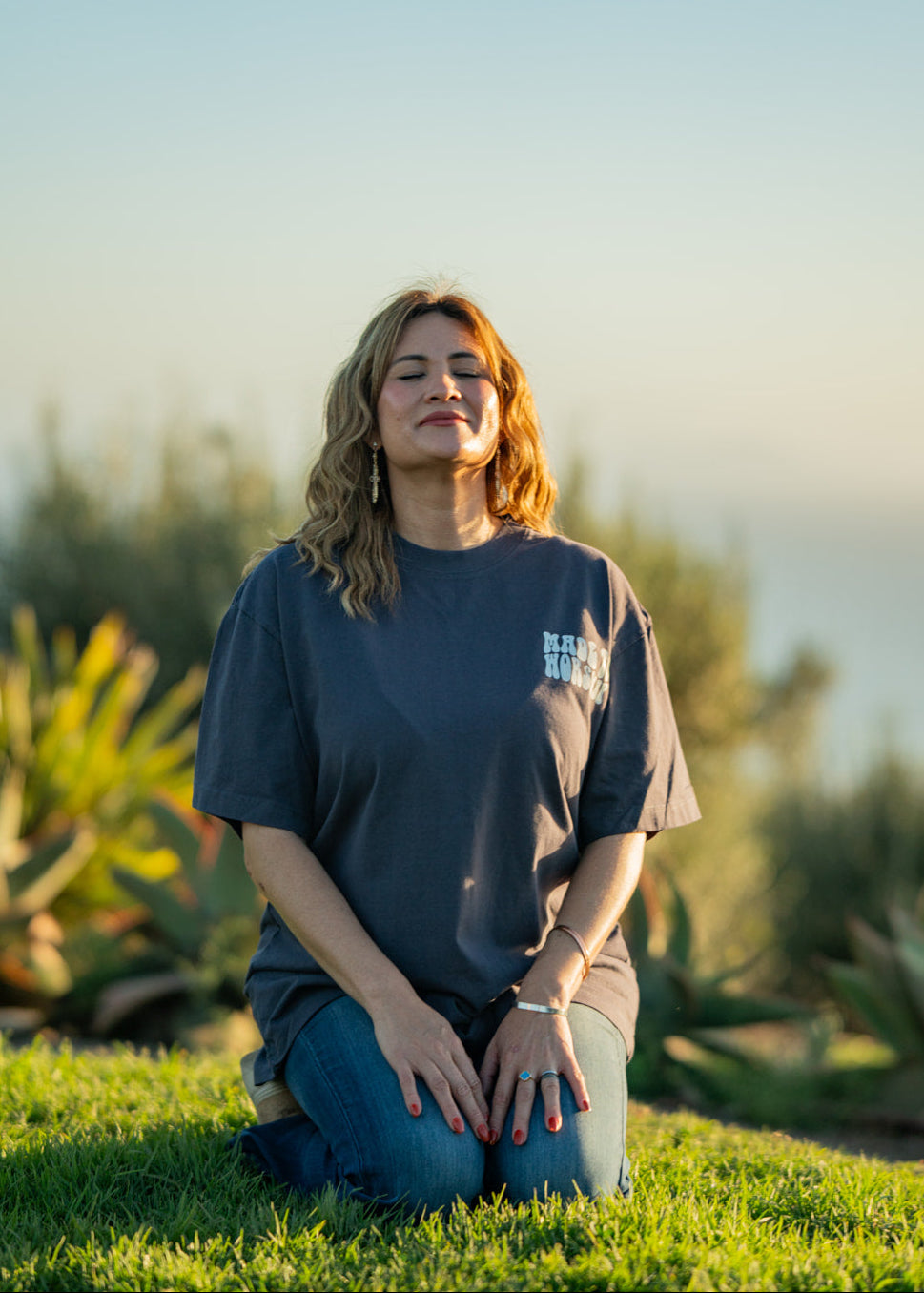 Woman sitting on grass with a scenic background
