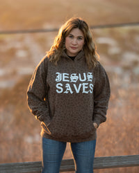 Person wearing a hoodie with 'Jesus Saves' text in an outdoor setting